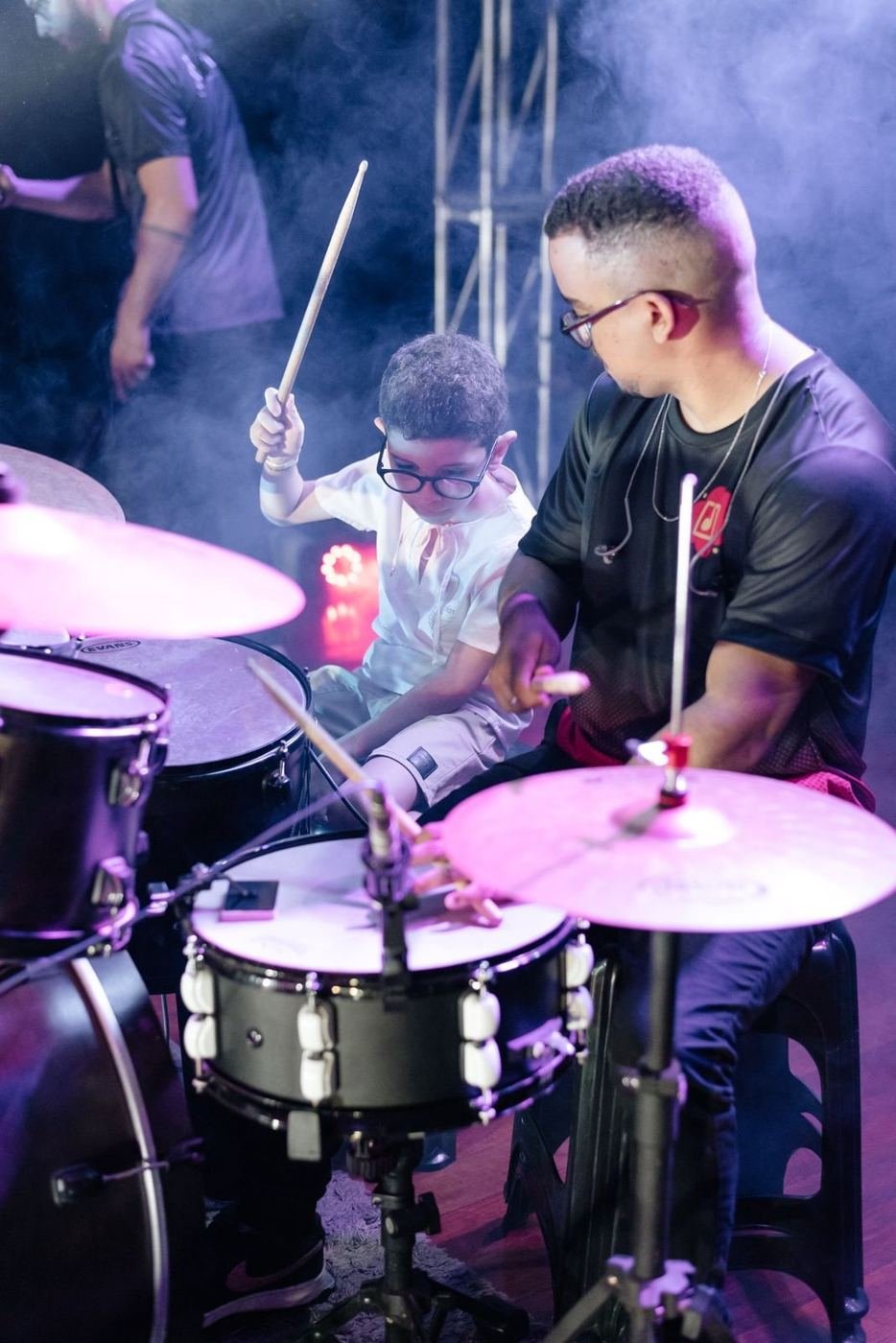 Aluno tocando bateria com o professor no Ateliê de Música